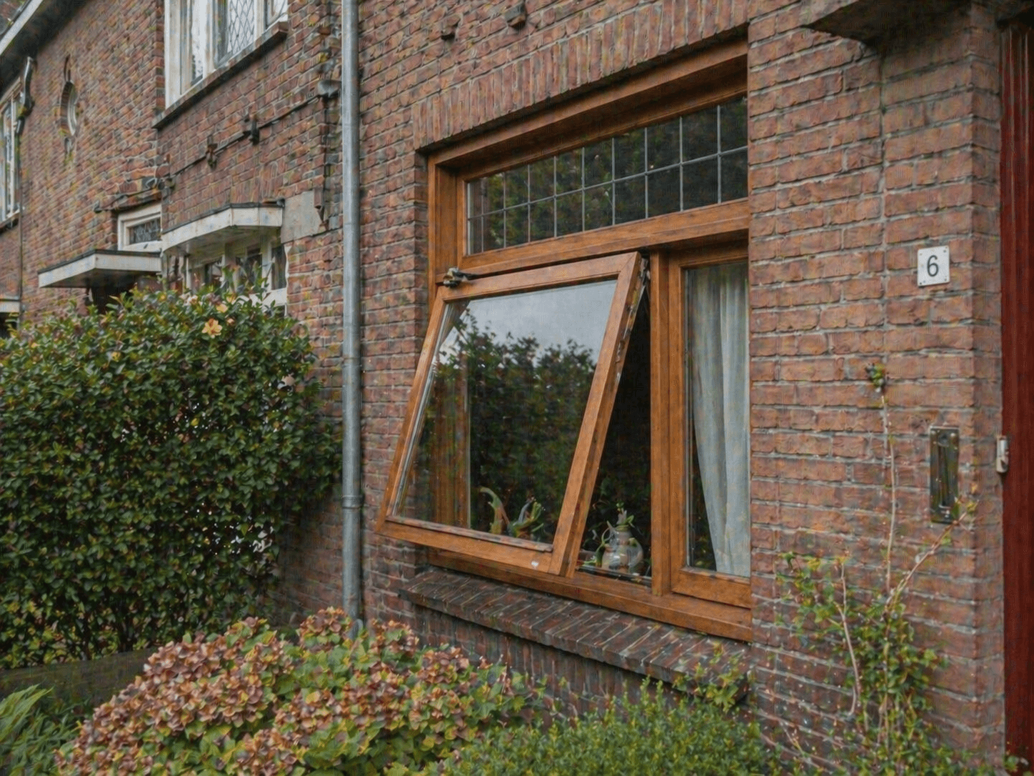 Jaren-30 woning met houten valraam in klassieke bakstenen gevel