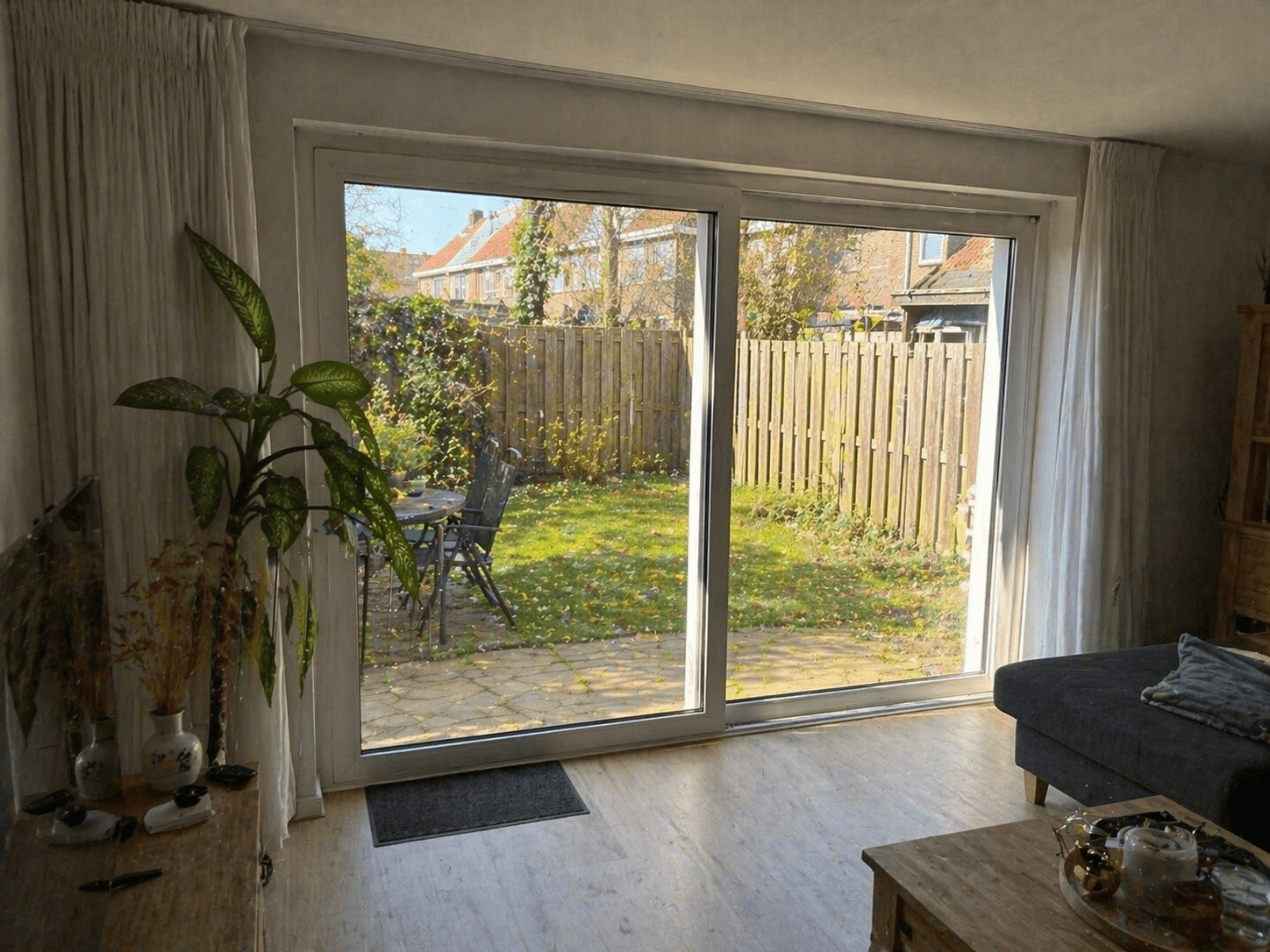 Moderne woonkamer met nieuwe kunststof schuifpui en doorkijk naar tuin