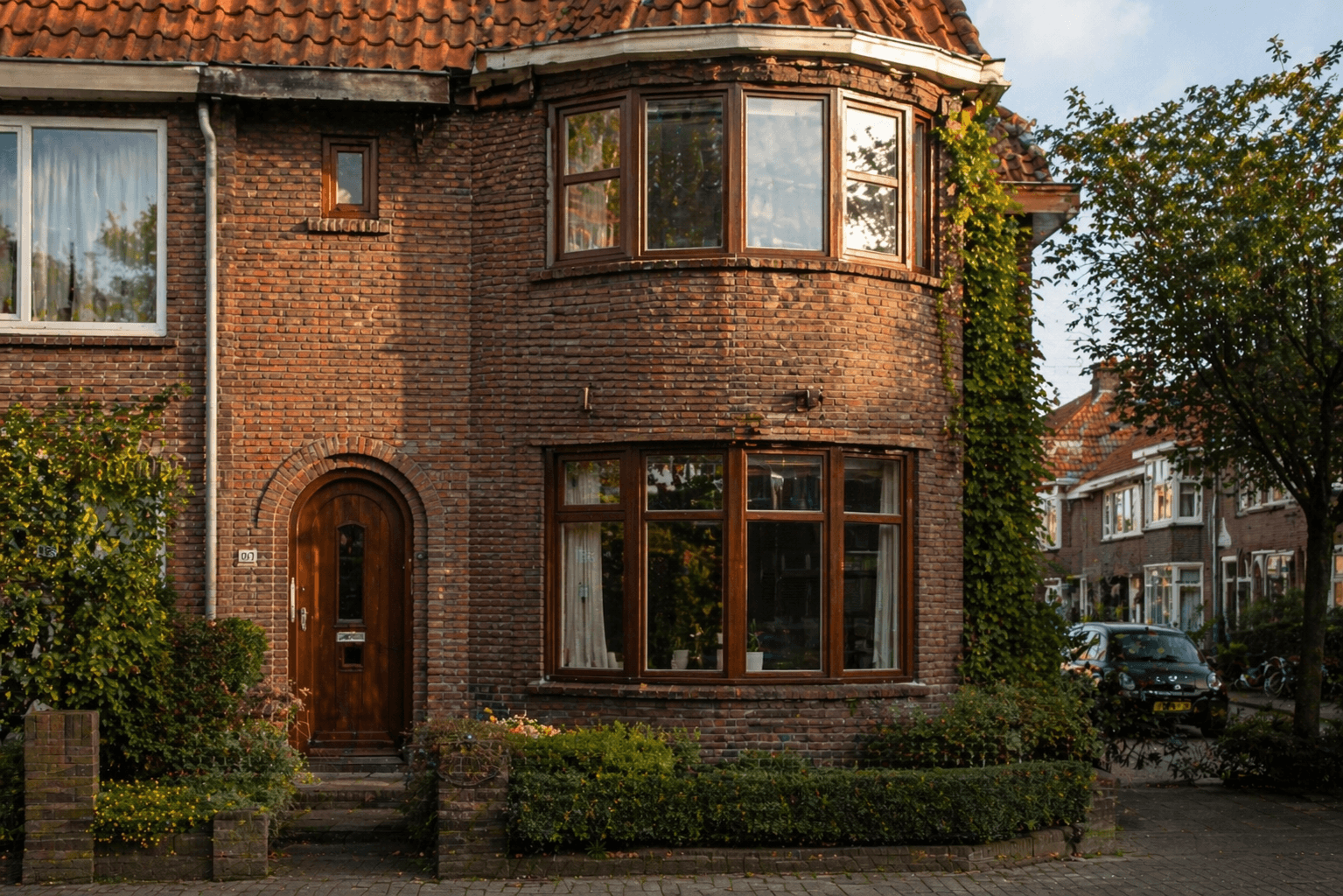 Jaren-30 hoekhuis met houten kozijnen en erker, klassieke bakstenen gevel