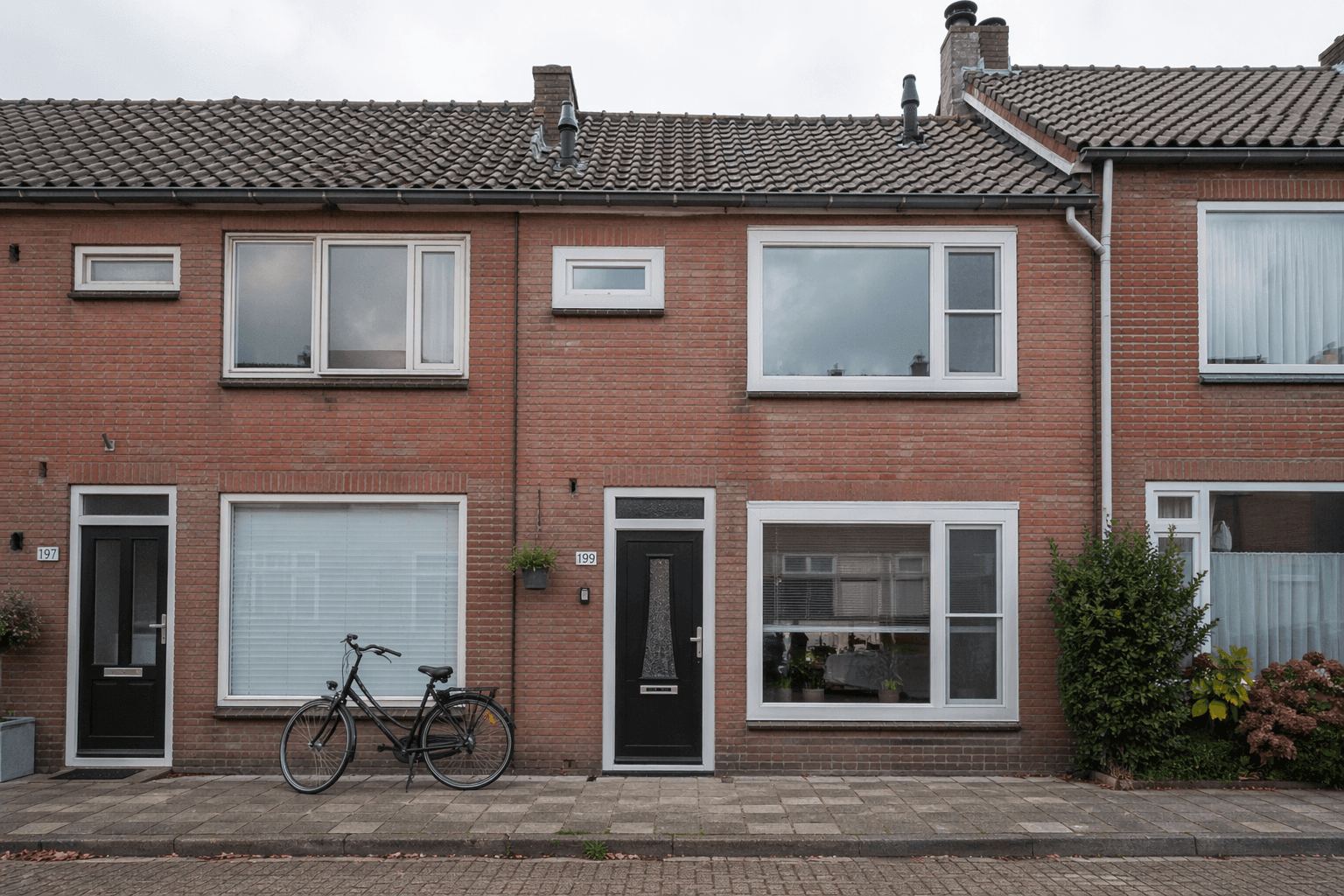 Rijtjeswoning met witte kunststof kozijnen in rode baksteengevel