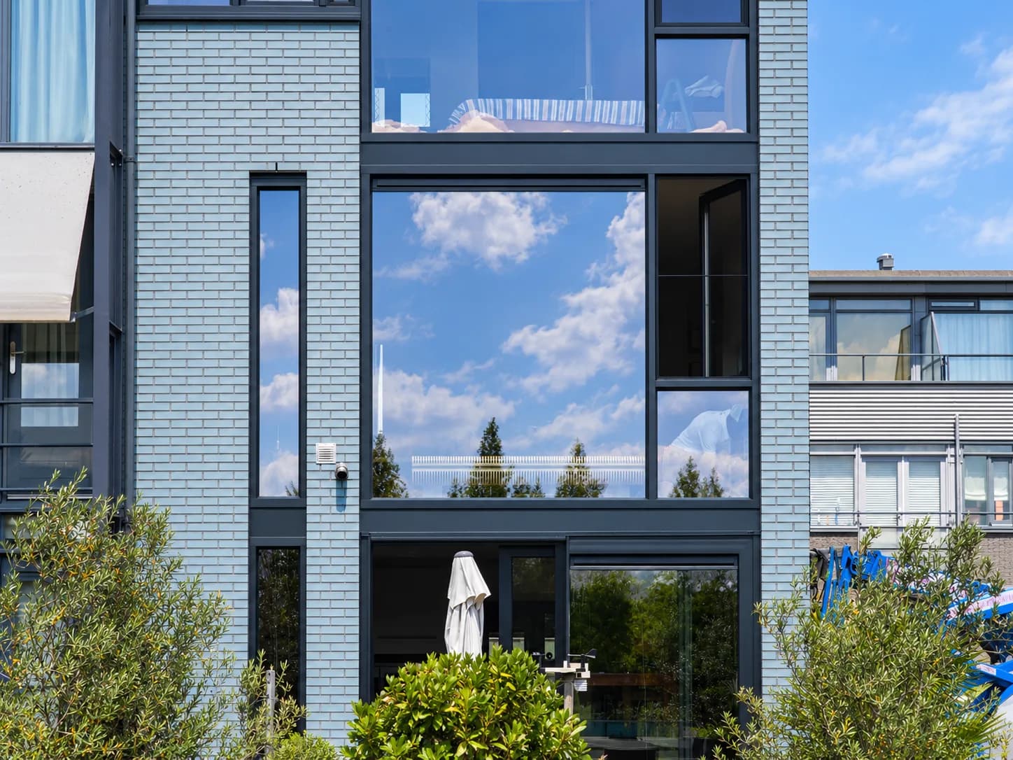 Hoge gevel met grote antraciete kozijnen en een tuin ervoor