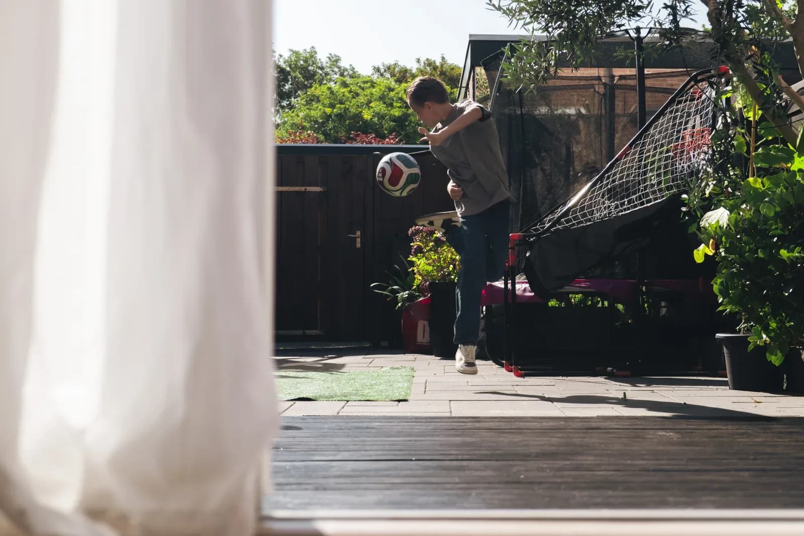Kind speelt in de tuin, gezien door het raam van de woonkamer
