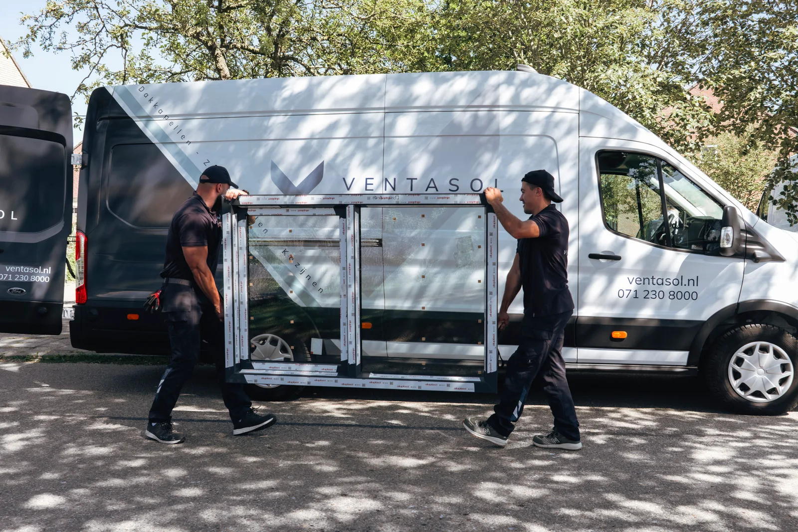 Twee monteurs van Ventasol dragen een nieuw kozijn uit de bus