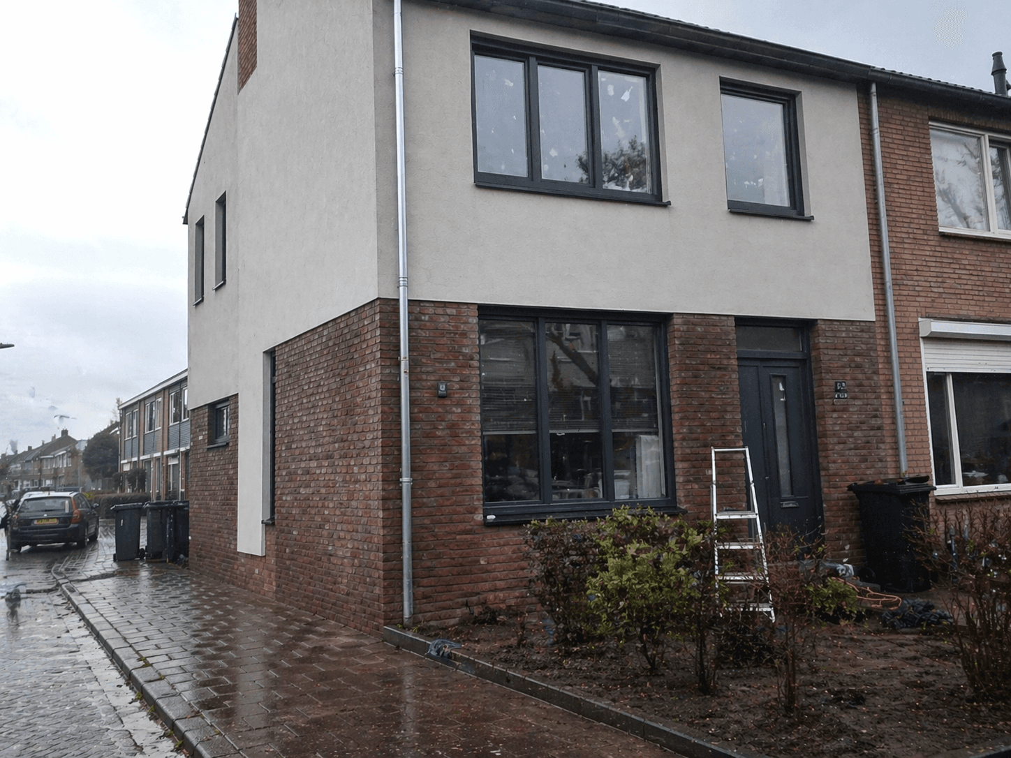 Hoekhuis tijdens een verbouwing met net geplaatste antraciete kozijnen en een ladder voor de gevel